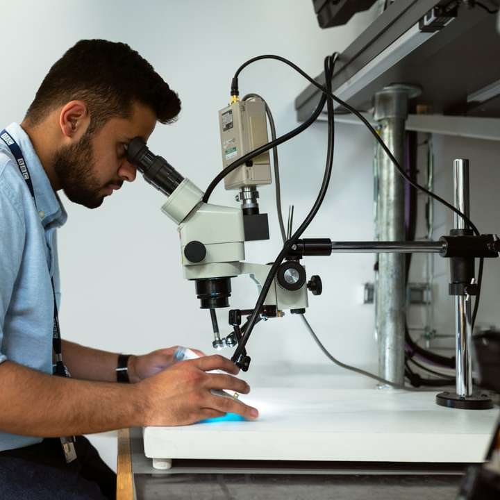 Männlicher Rundfunkingenieur verwendet Mikroskop Schiebepuzzle online
