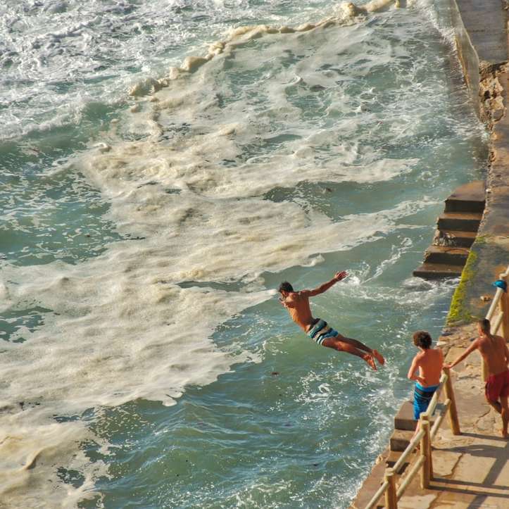 mężczyzna skacze po morzu na fotografii ostrości puzzle przesuwne online