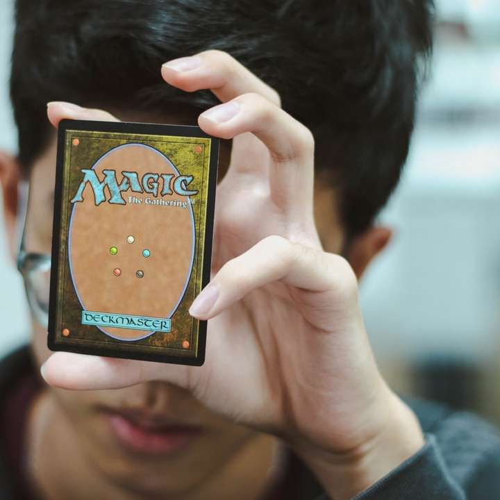garoto segurando Magic: The Gathering trading card puzzle online
