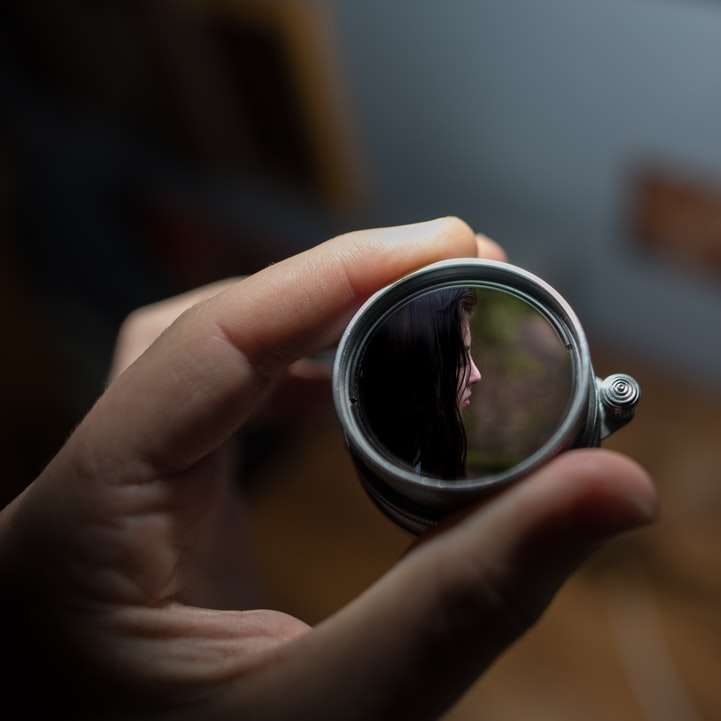 osoba, která drží kulaté šedé zrcadlo selektivní zaměření fotografie online puzzle