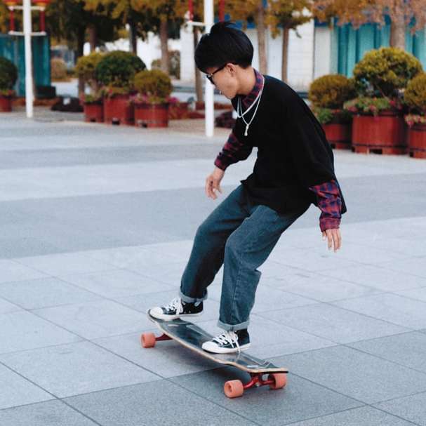 άνδρας φορώντας μαύρο πουλόβερ ιππασία skateboard συρόμενο παζλ online