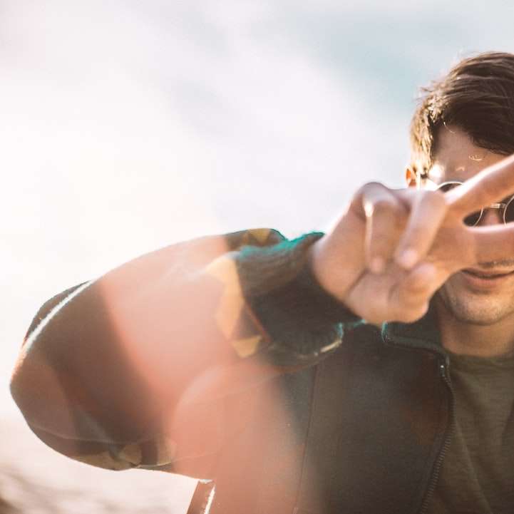 shallow focus photography of smiling man doing peace sign online puzzle