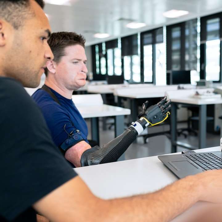 мъж в синя тениска на врата на екипажа, използвайки черен преносим компютър онлайн пъзел