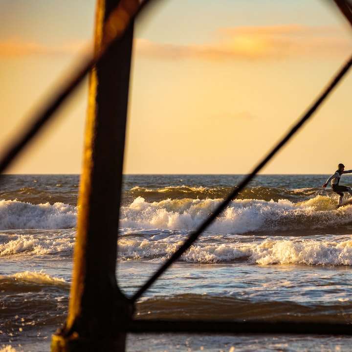 Surfowanie w kierunku molo o zachodzie słońca. puzzle przesuwne online