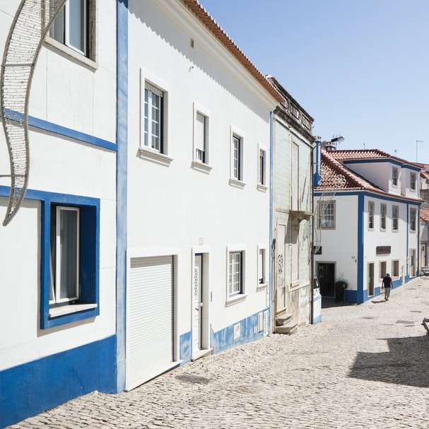 graue Straße mit weißen und blauen Betonhäusern gesäumt Online-Puzzle