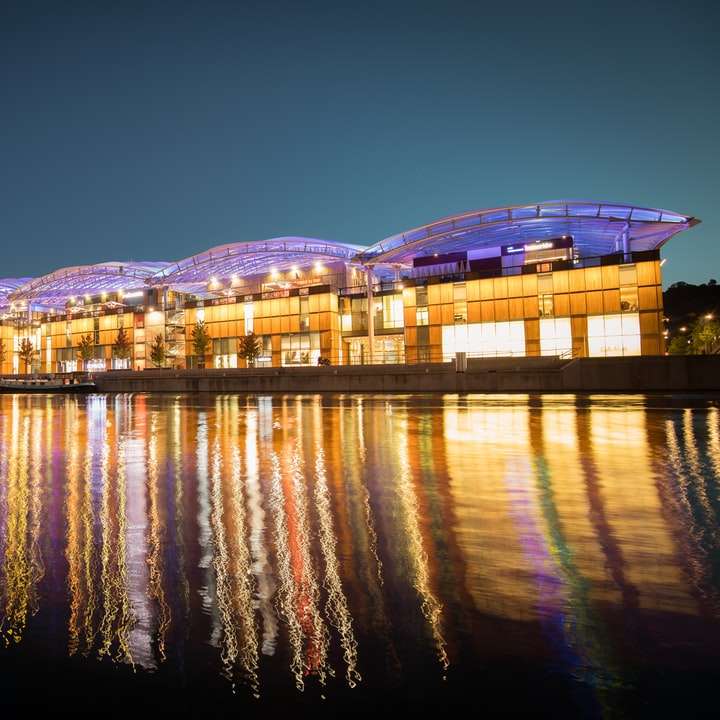 панорамна фотографія освітлених будинків біля водойми онлайн пазл
