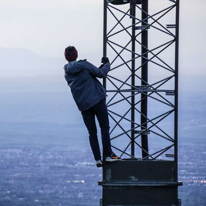 muž lezení na věži poblíž budov ve dne online puzzle