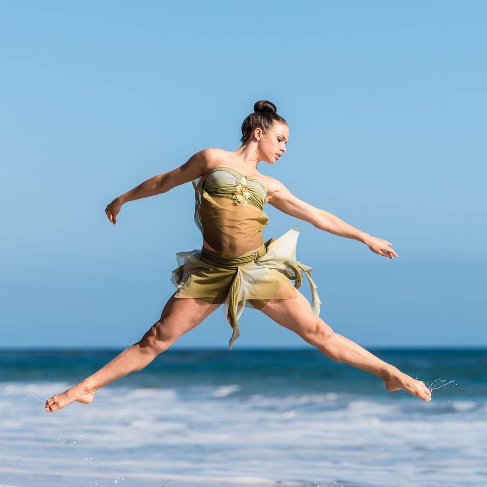 kvinna dansar bredvid vattnet på dagtid Pussel online