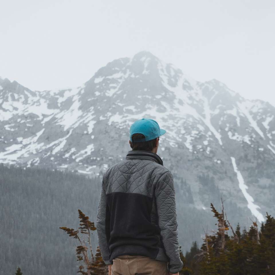 Ο άνθρωπος κοιτάζει το χιονισμένο βουνό συρόμενο παζλ online