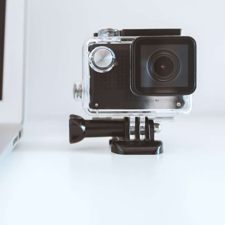 μαύρη κάμερα δράσης δίπλα σε λευκό φορητό υπολογιστή συρόμενο παζλ online