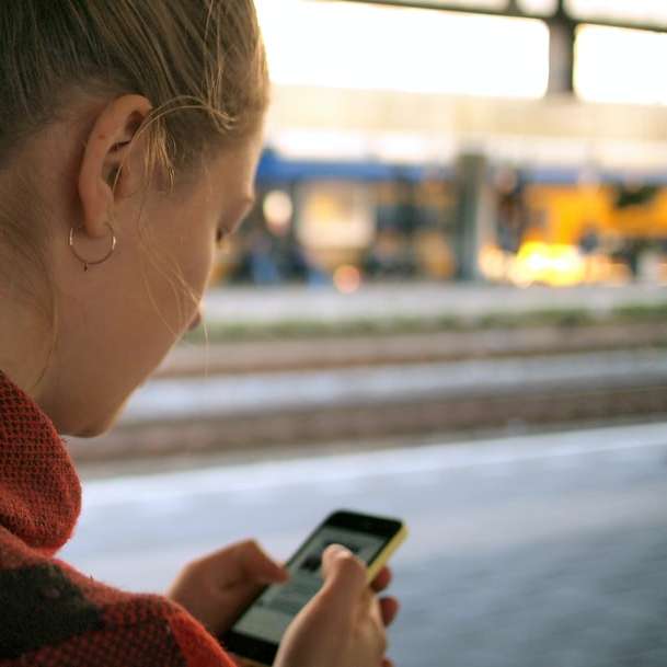 жена държи телефон плъзгащ се пъзел онлайн