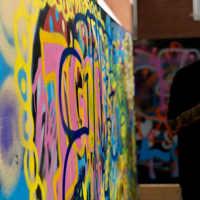 Hombre de pie y usando un teléfono inteligente cerca de la pared con murales rompecabezas en línea