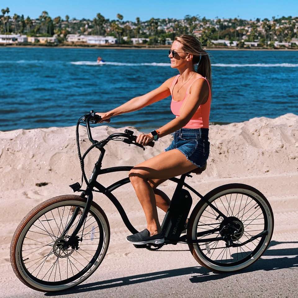 Att rida på en Tower Electric Bike längs stranden. Pussel online