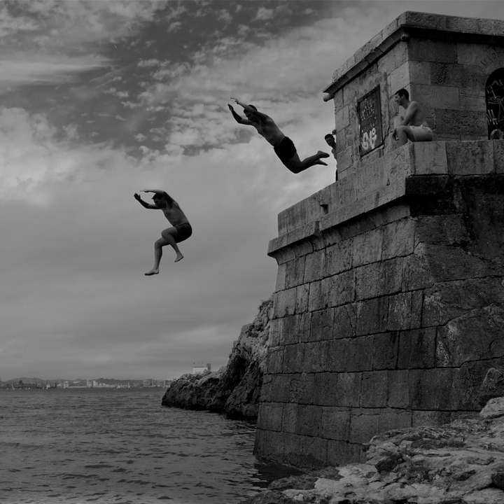 two men dive into the sea water from concrete building online puzzle