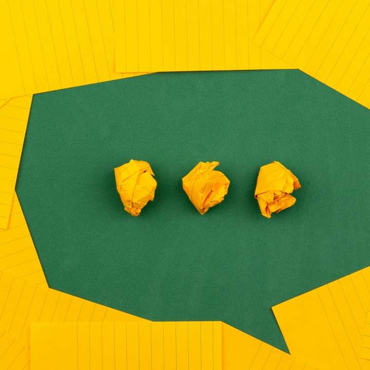 três papéis amarelos amassados ​​na superfície verde puzzle online
