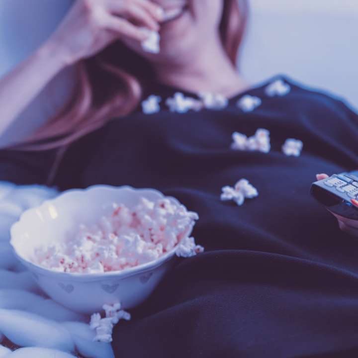Frau, die auf Bett liegt, während sie Blätterteig isst Schiebepuzzle online