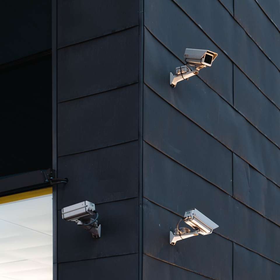 trzy białe kamery CCTV na ścianie budynku puzzle przesuwne online