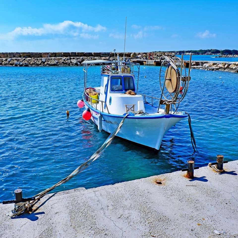 biała i niebieska łódź na doku morskim w ciągu dnia puzzle online