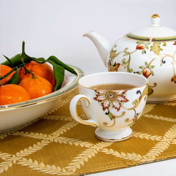 weiße und bunte Tassen, gefüllt mit Tee neben Früchten Schiebepuzzle online