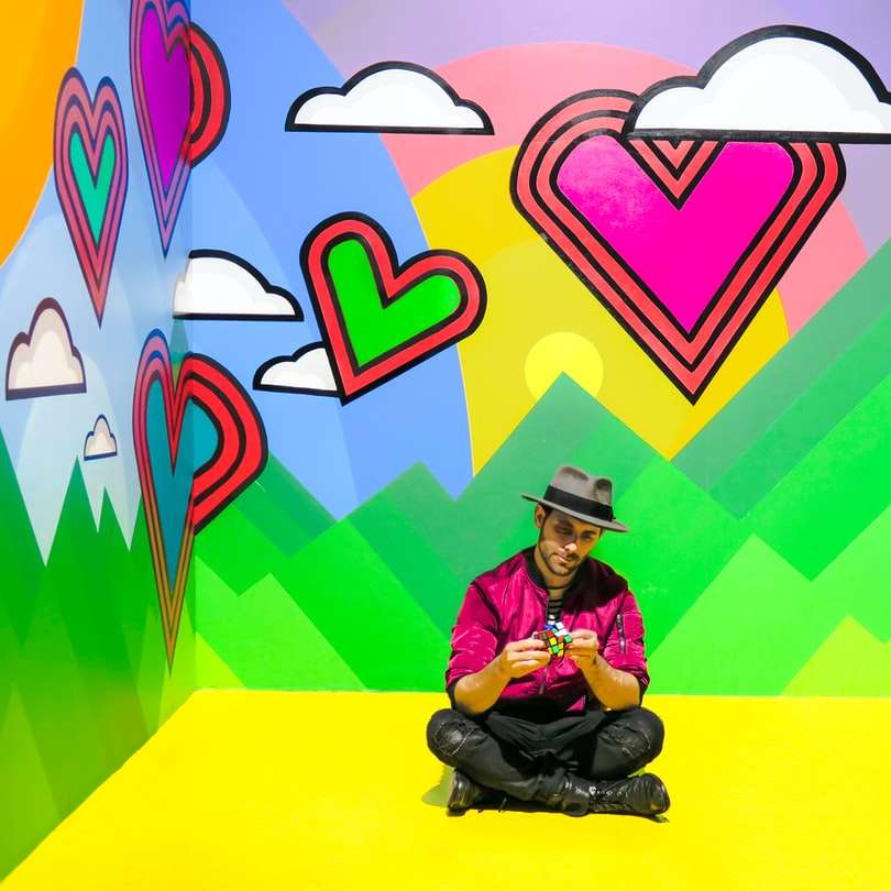 homme assis sur une salle de papier peint 3D multicolore puzzle en ligne
