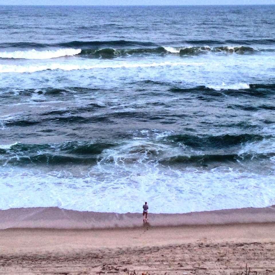 мъж, стоящ на брега на морето плъзгащ се пъзел онлайн