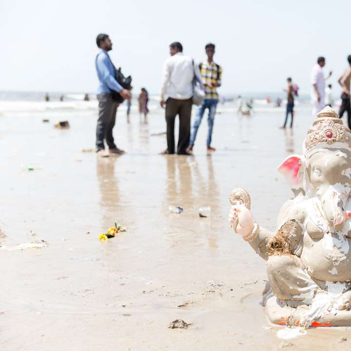 Lord Ganesh Figur auf weißem Sand in der Nähe von Menschen während des Tages Online-Puzzle