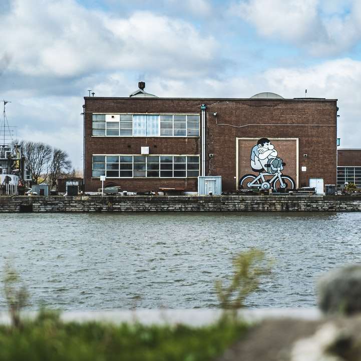 hnědá betonová budova poblíž vodní plochy během dne posuvné puzzle online