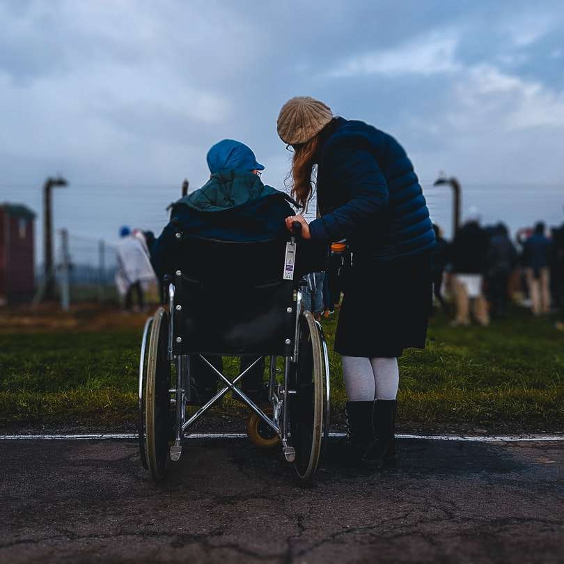 mujer de pie cerca de persona en silla de ruedas rompecabezas en línea