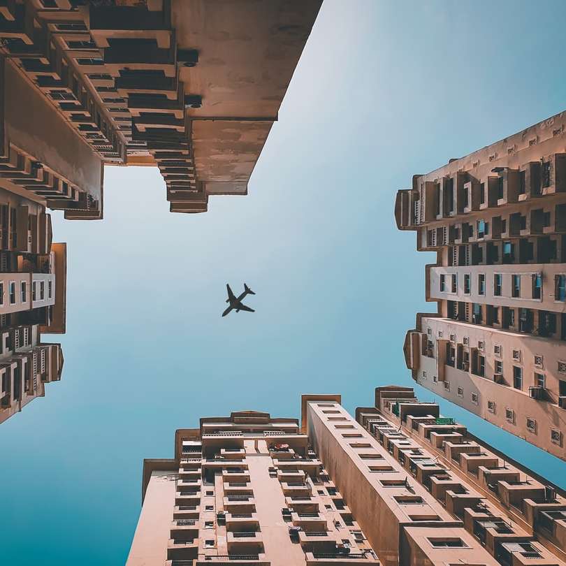 Olhe para cima tiro de um avião passando por cima dos edifícios puzzle online