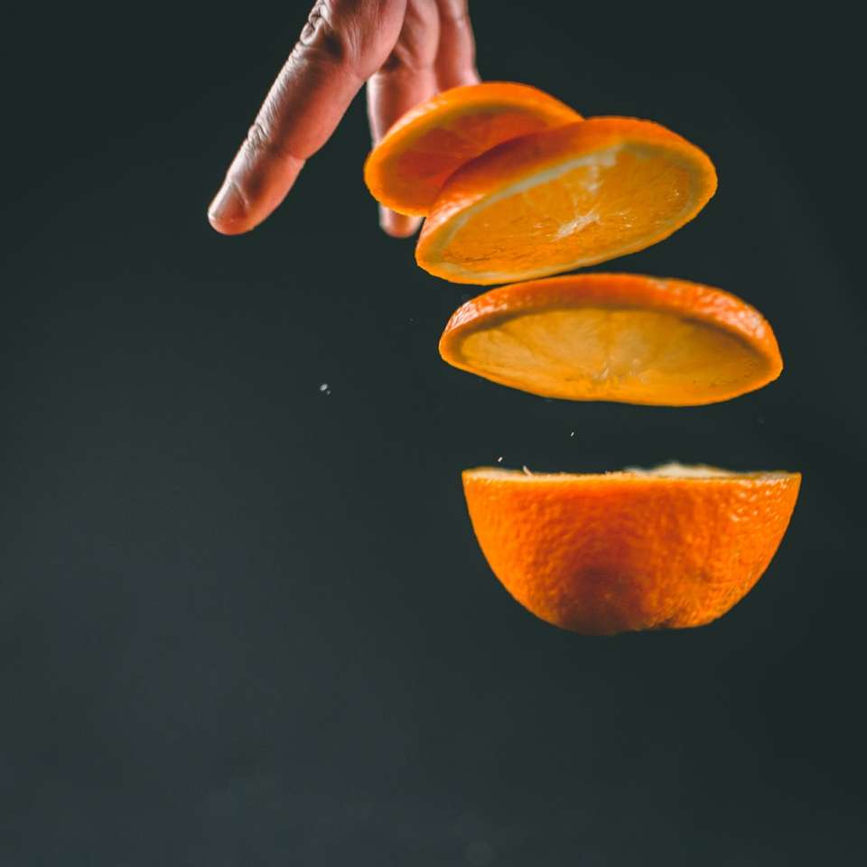 person holding sliced orange fruit sliding puzzle online