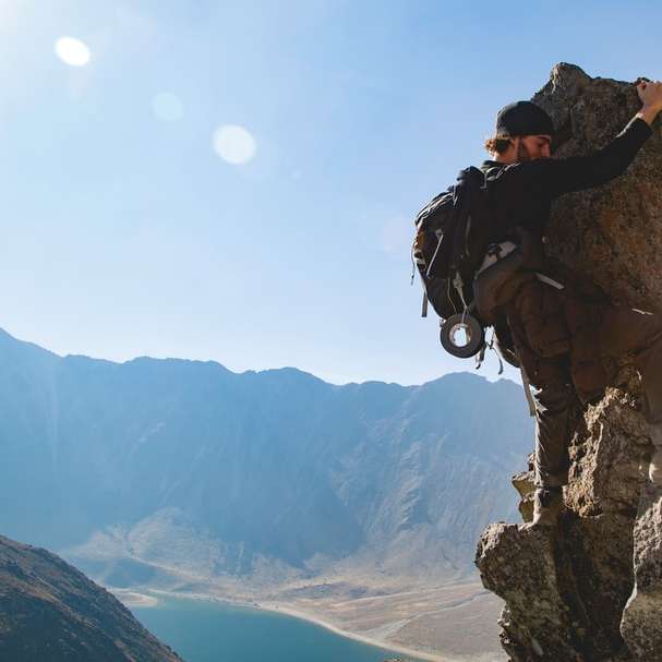 homem escalando formação rochosa durante o dia puzzle online
