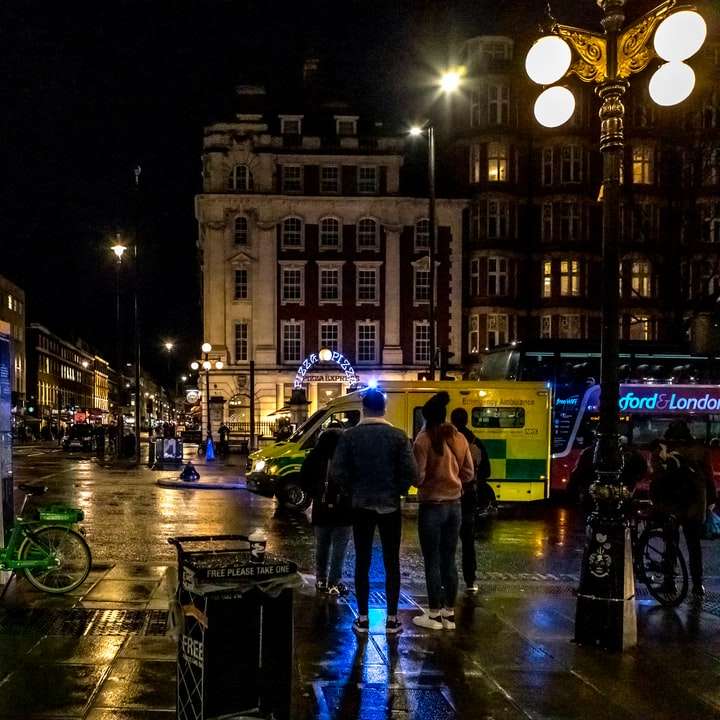 Menschen, die während der Nacht auf dem Bürgersteig in der Nähe des Gebäudes gehen Schiebepuzzle online