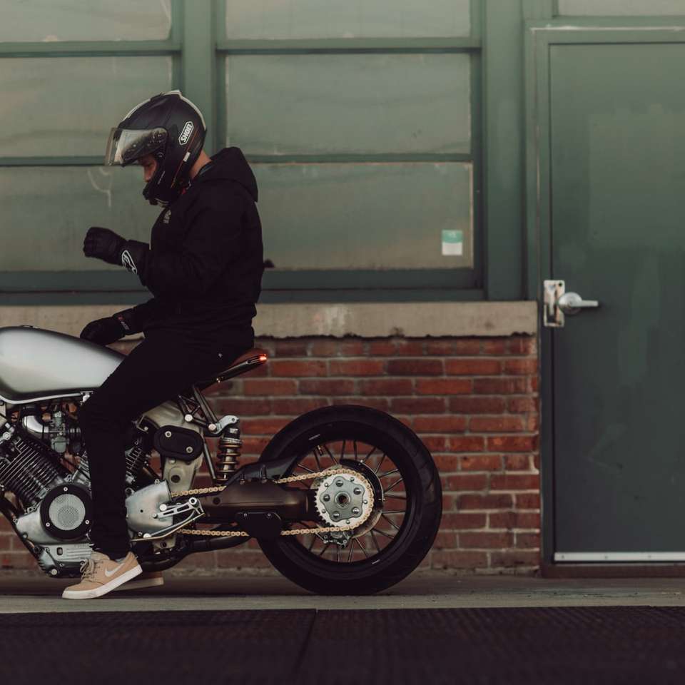 Mann, der ein Motorrad auf der Straßenseite fährt Online-Puzzle