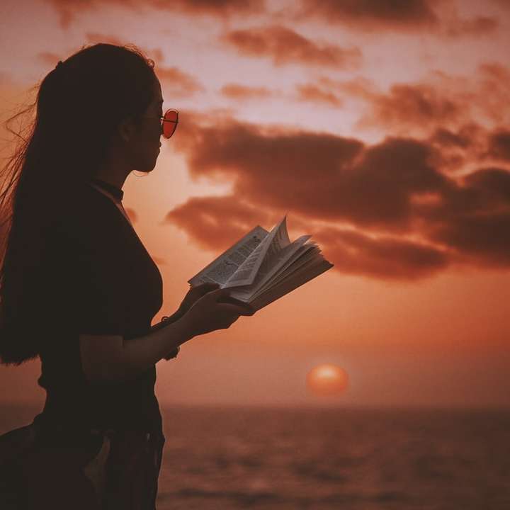 kobieta trzyma książkę, patrząc na zbiornik wodny puzzle przesuwne online