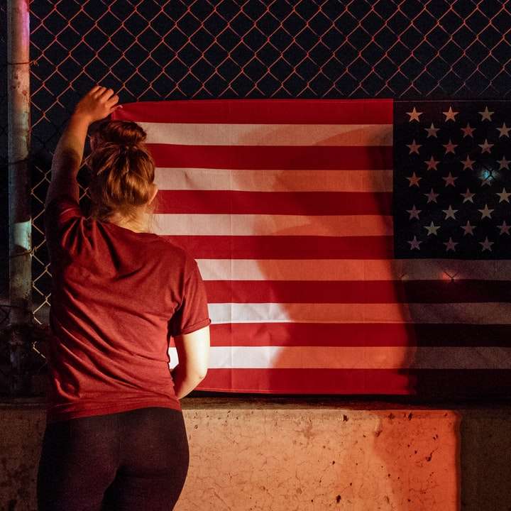 灰色の金網の近くに米国旗を保持している女性と男性 オンラインパズル