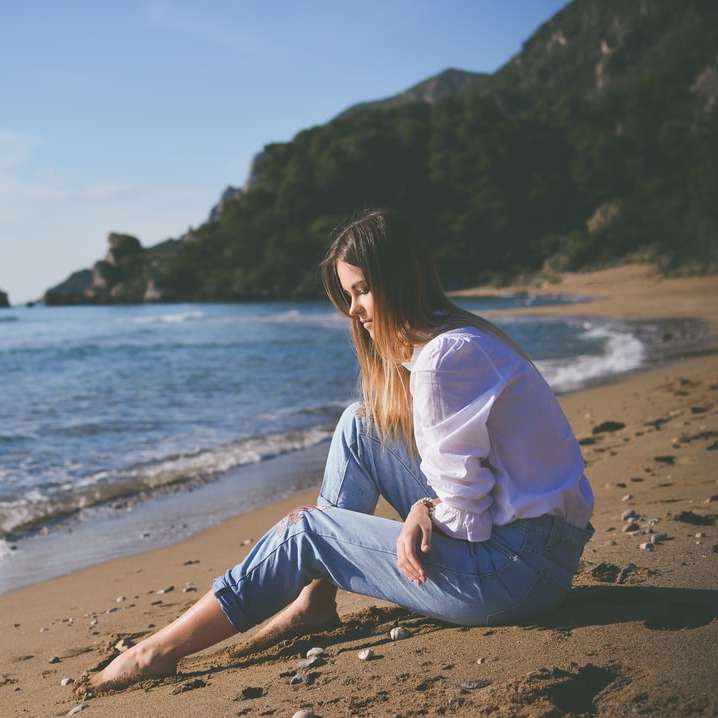 woman sitting on beach shore during daytime sliding puzzle online