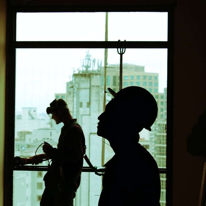 two men wearing hard hat standing near clear glass window online puzzle