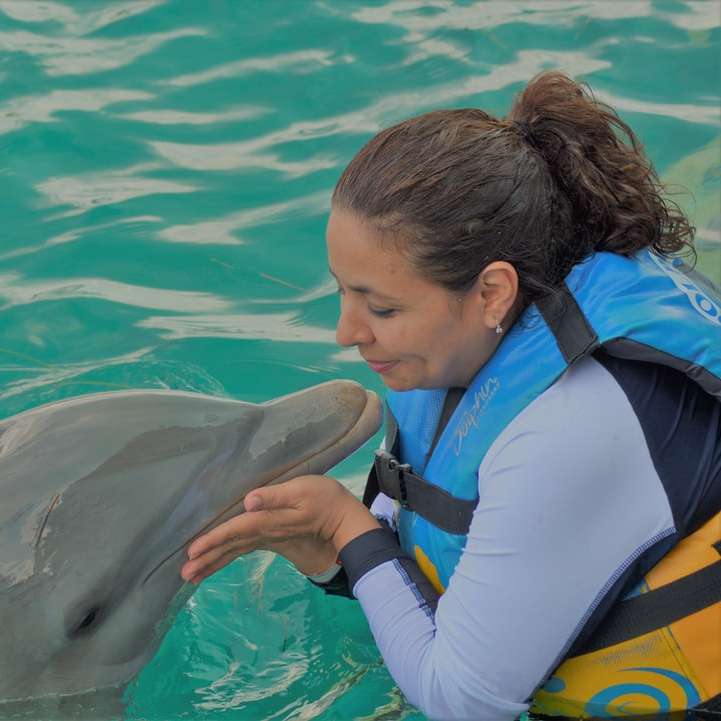 mulher brincando com um golfinho em um corpo de água puzzle online