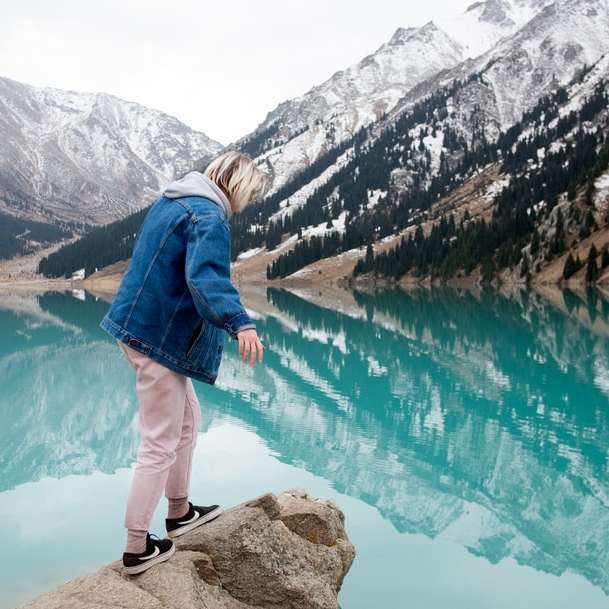 mulher de pé na rocha de frente para o lago puzzle deslizante online