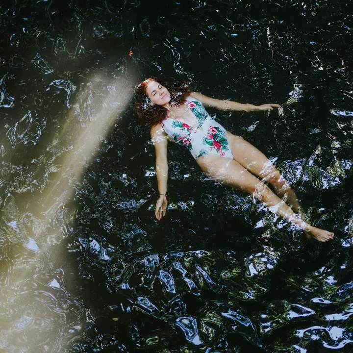 水の上に横たわっている青と白の花のビキニの女性 スライディングパズル・オンライン