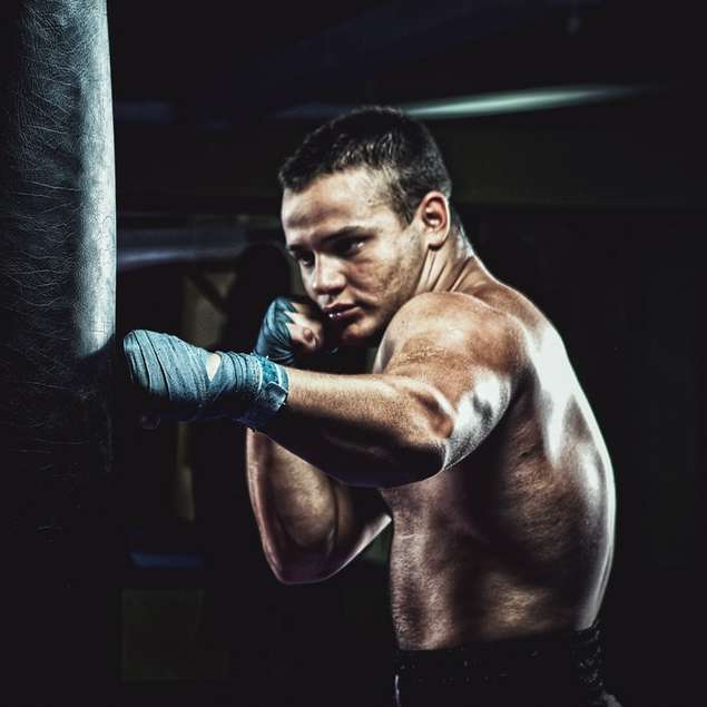 Young man punching a bag in the gym sliding puzzle online