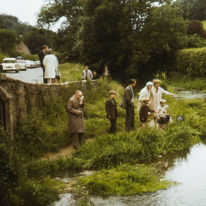 хора, стоящи на зелена трева близо до реката през деня плъзгащ се пъзел онлайн