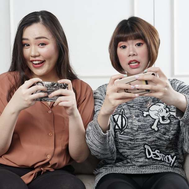 La donna asiatica gioca al gioco per cellulare su smartphone e vinci puzzle scorrevole online