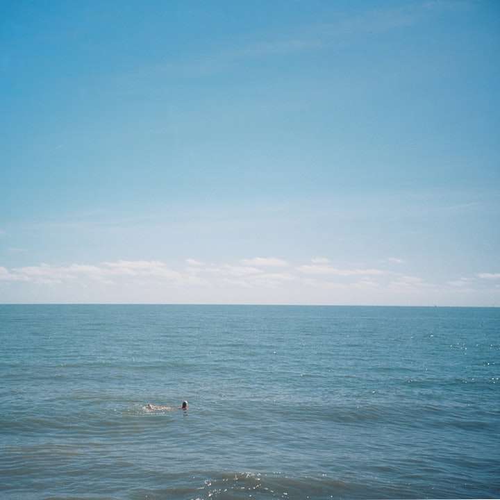 persona que practica surf en el mar bajo un cielo azul durante el día rompecabezas en línea