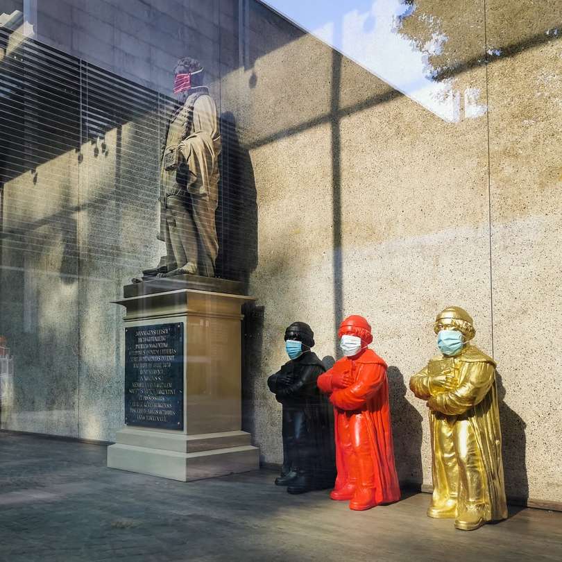 Трое мужчин в красной мантии стоят возле статуи днем онлайн-пазл