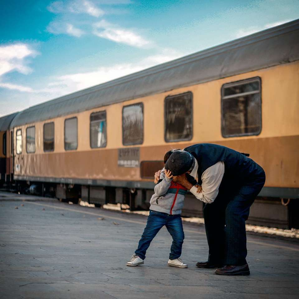 hombre y niño jugando al lado del tren rompecabezas en línea