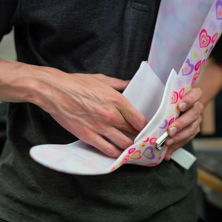 Person, die weißes und rosa Blumentextil hält Online-Puzzle