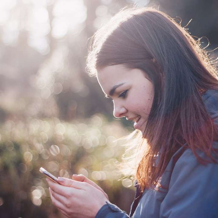 Frau hält Telefon lächelnd Schiebepuzzle online