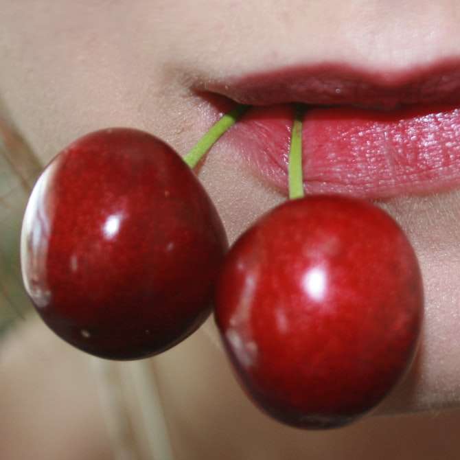 person with red round fruit on mouth sliding puzzle online