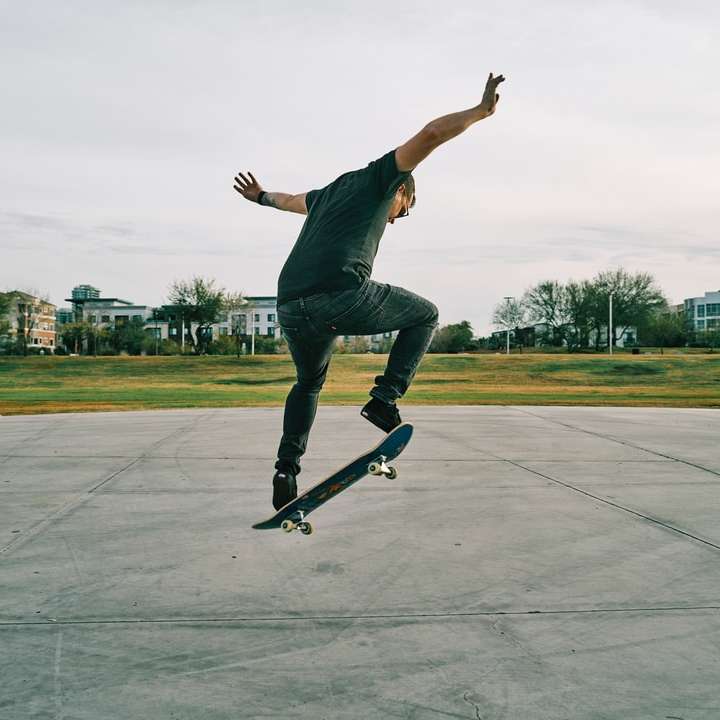 мъж в черна тениска и сини дънкови дънки, каране на скейтборд плъзгащ се пъзел онлайн